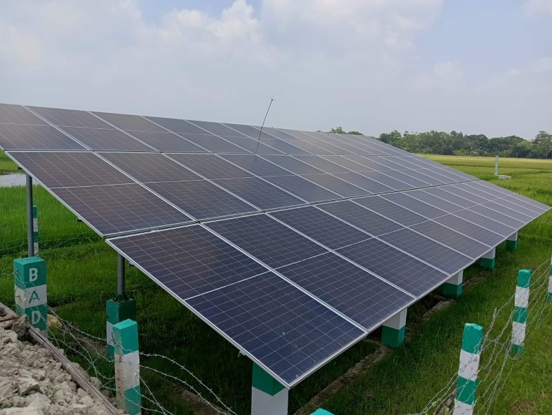আনোয়ারার হাইলধর ইউনিয়নে বিএডিসির তত্ত্বাবধানে স্থাপিত সোলার প্যানেল অ্যারে। সবুজ ধানক্ষেতের মাঝখানে এই নীল প্যানেলগুলো প্রতিদিন সূর্যের আলোকে পরিণত করছে কৃষকের স্বপ্নে। ছবিতে দেখা যাচ্ছে বিএডিসির লোগোসহ সুরক্ষিত বেড়ার ভেতরে সাজানো সোলার প্যানেলের বিন্যাস।